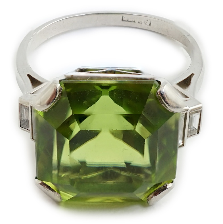 A 1920's platinum and single stone asscher cut peridot set dress ring, with four stone graduated baguette cut diamond set shoulders